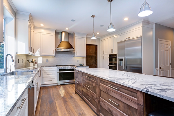A new custom kitchen with quartz countertops, wooden cabinets and floors withs stainless steel appliances